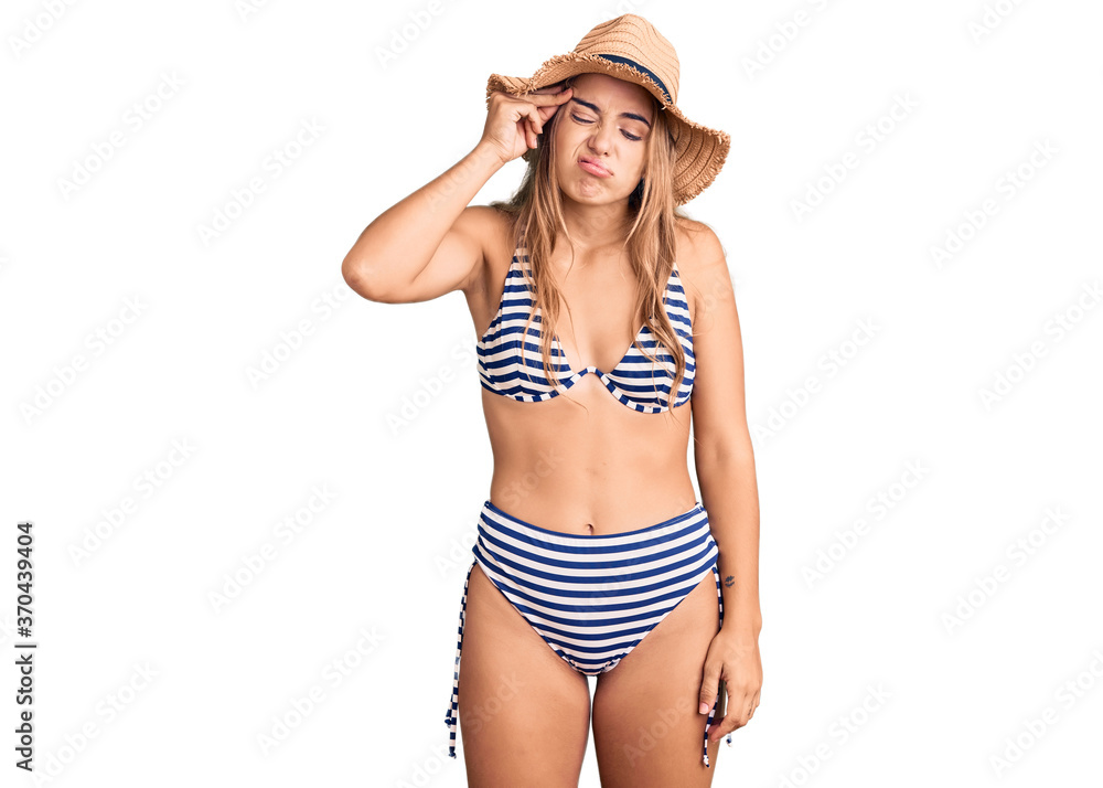 Young beautiful blonde woman wearing bikini and hat worried and stressed about a problem with hand on forehead, nervous and anxious for crisis Young beautiful blonde woman wearing bikini and hat worried and stressed about a problem with hand on forehead, nervous and anxious for crisis