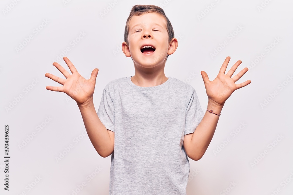 Cute blond kid wearing casual clothes celebrating mad and crazy for success with arms raised and closed eyes screaming excited. winner concept Cute blond kid wearing casual clothes celebrating mad and crazy for success with arms raised and closed eyes screaming excited. winner concept