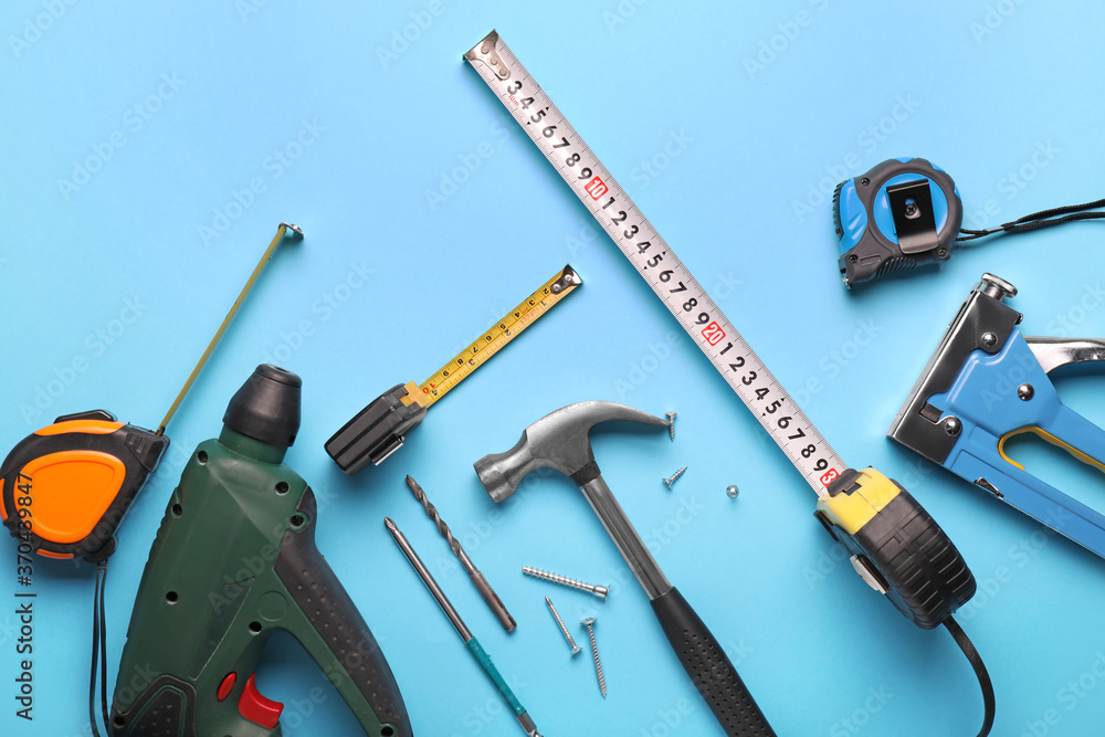 Measuring tapes with builder's supplies on color background