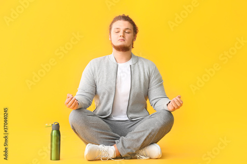 Meditating young man on color background © Pixel-Shot