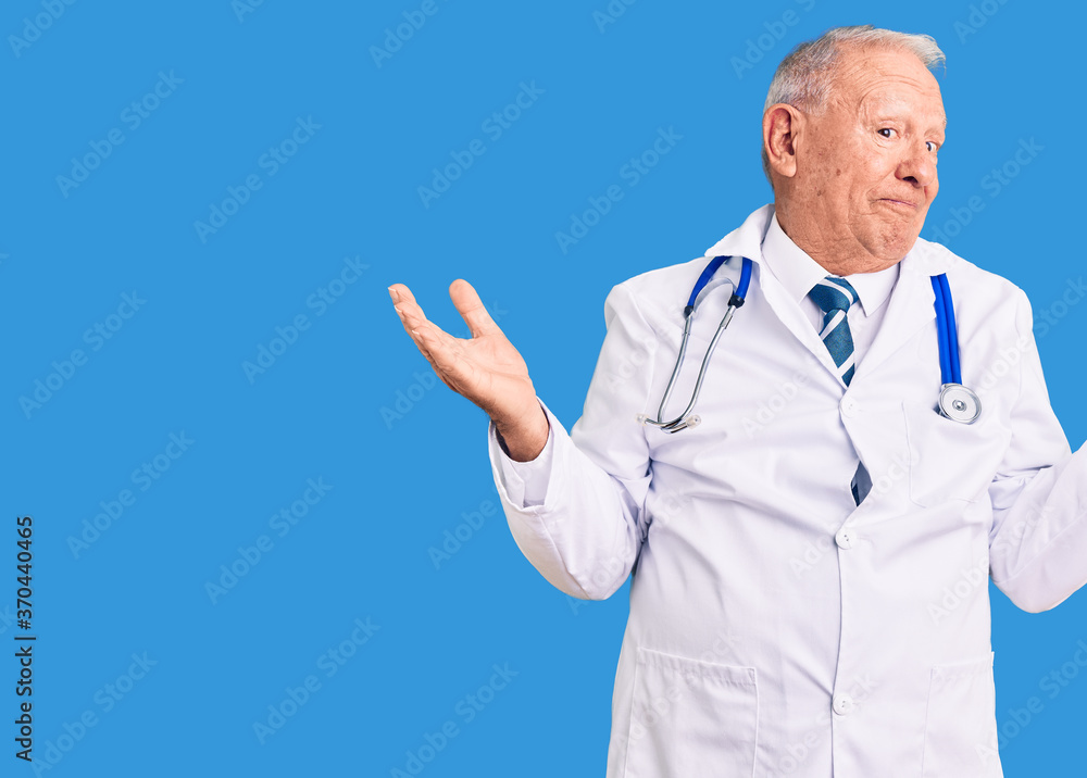 Senior handsome grey-haired man wearing doctor coat and stethoscope smiling showing both hands open palms, presenting and advertising comparison and balance Senior handsome grey-haired man wearing doctor coat and stethoscope smiling showing both hands open palms, presenting and advertising comparison and balance