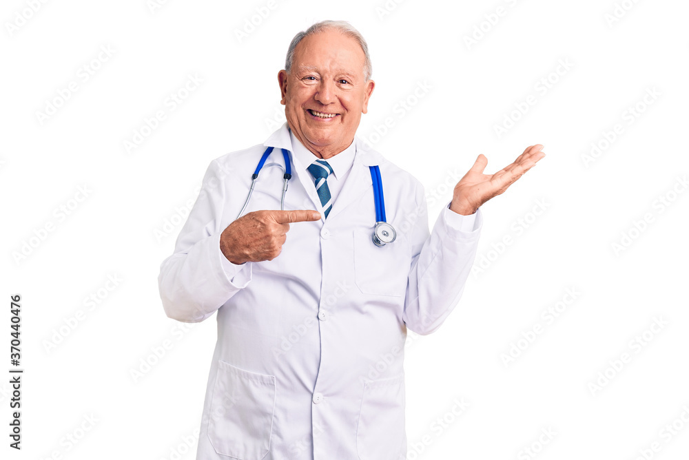Senior handsome grey-haired man wearing doctor coat and stethoscope amazed and smiling to the camera while presenting with hand and pointing with finger. Senior handsome grey-haired man wearing doctor coat and stethoscope amazed and smiling to the camera while presenting with hand and pointing with finger.