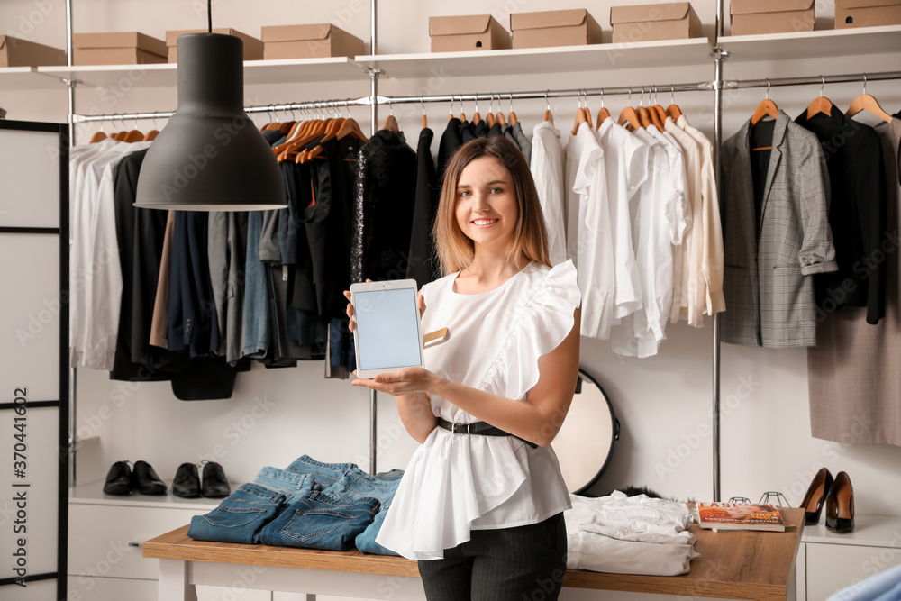 Female seller with tablet computer in modern clothes store Female seller with tablet computer in modern clothes store