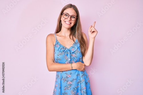 Young blonde girl wearing casual clothes and glasses smiling happy pointing with hand and finger to the side © Krakenimages.com