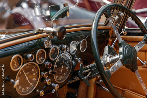 Selective focus, interior view of classic and vintage detail of gauge, switches, button, meter and steering wheel on black control panel dashboard inside old antique convertible car. © Peeradontax