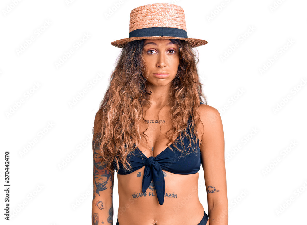 Young hispanic woman with tattoo wearing bikini and summer hat looking sleepy and tired, exhausted for fatigue and hangover, lazy eyes in the morning. Young hispanic woman with tattoo wearing bikini and summer hat looking sleepy and tired, exhausted for fatigue and hangover, lazy eyes in the morning.
