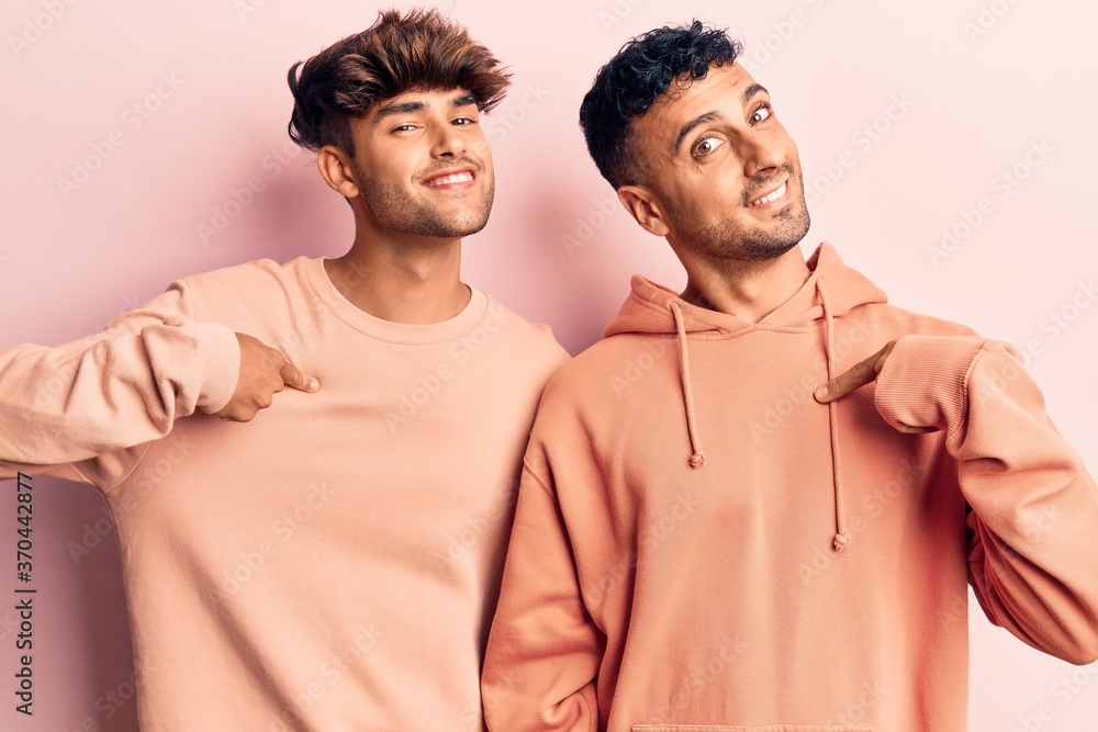 Young gay couple wearing casual clothes looking confident with smile on face, pointing oneself with fingers proud and happy. Young gay couple wearing casual clothes looking confident with smile on face, pointing oneself with fingers proud and happy.