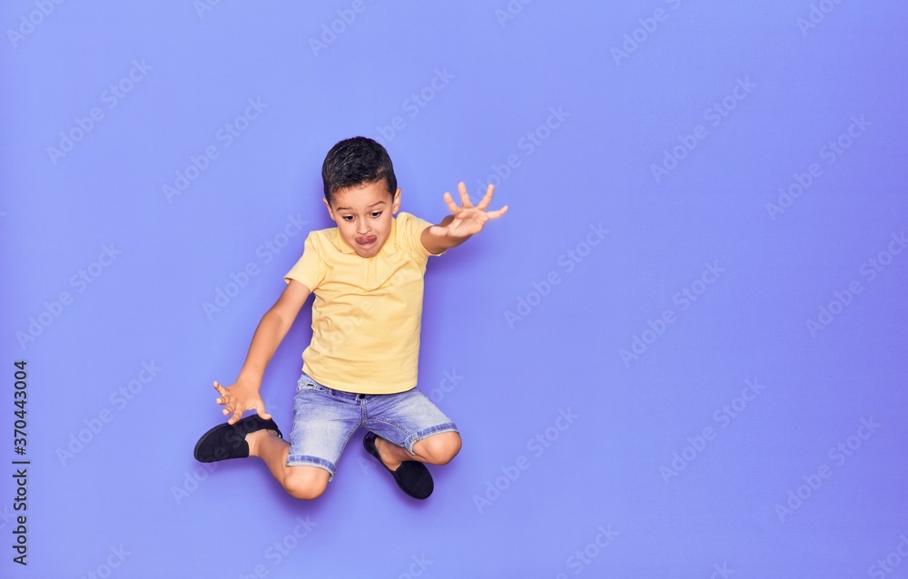 Adorable kid wearing casual clothes jumping over isolated purple background Adorable kid wearing casual clothes jumping over isolated purple background