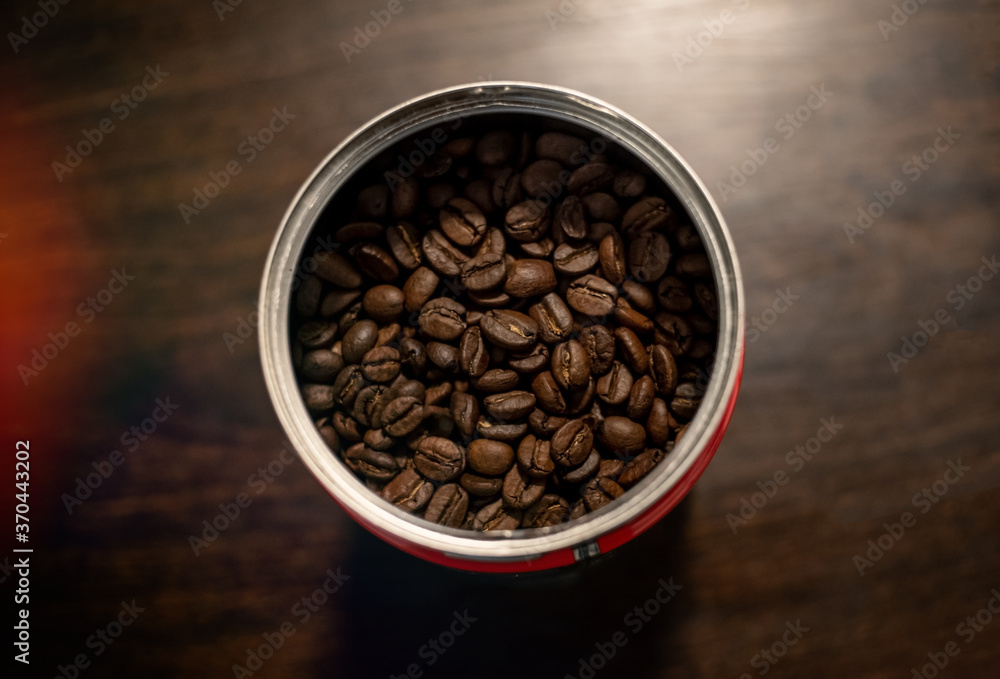 Fototapeta premium brown roasted coffee beans in a recipient on a wooden table