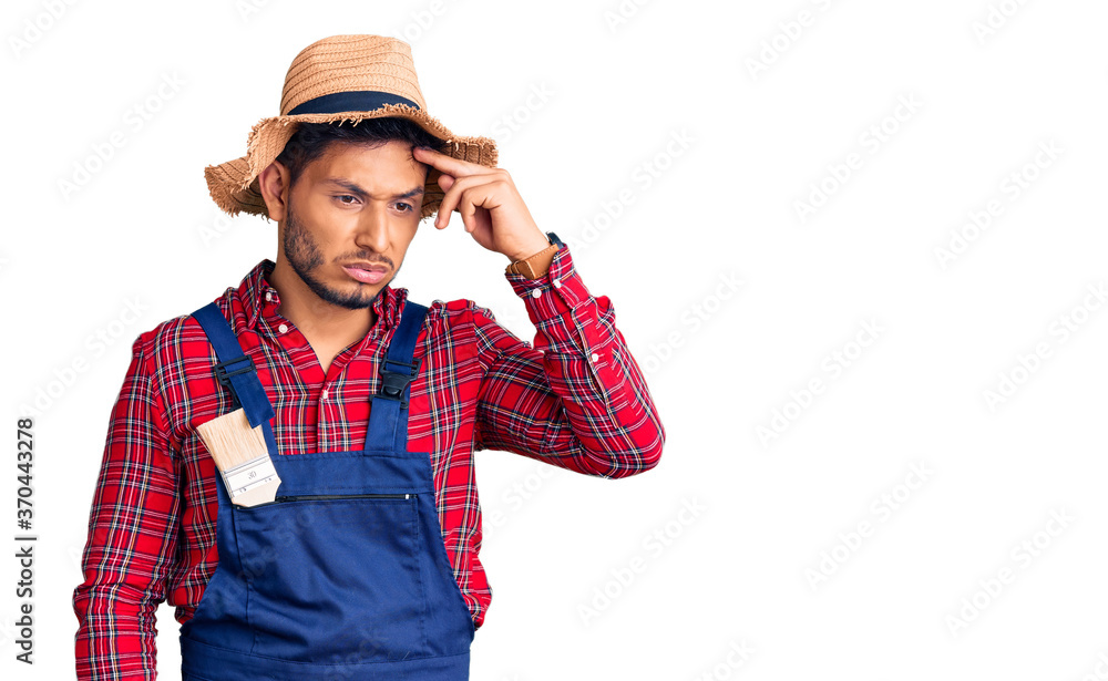 Handsome latin american young man weaing handyman uniform worried and stressed about a problem with hand on forehead, nervous and anxious for crisis Handsome latin american young man weaing handyman uniform worried and stressed about a problem with hand on forehead, nervous and anxious for crisis
