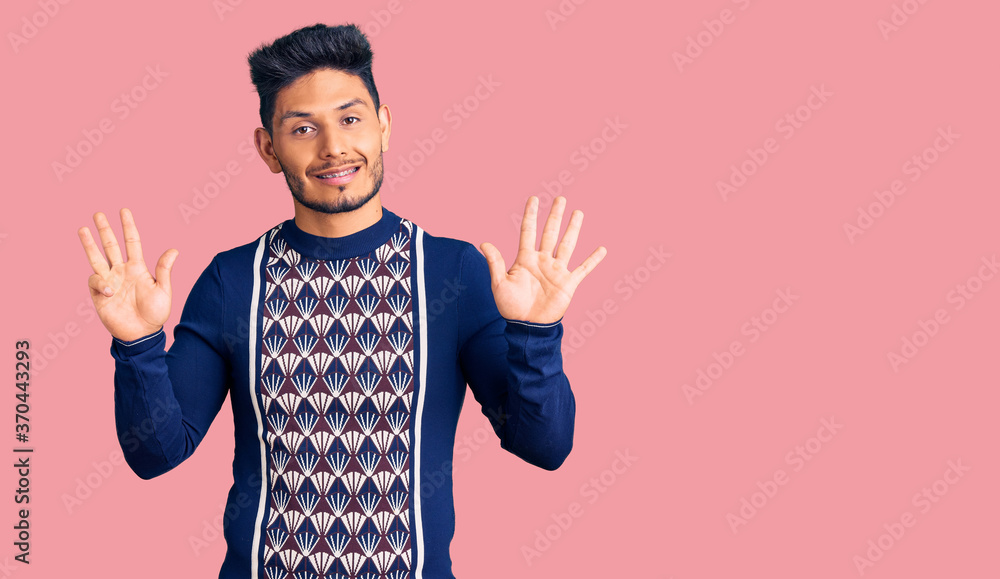 Naklejka premium Handsome latin american young man wearing casual winter sweater showing and pointing up with fingers number eight while smiling confident and happy.