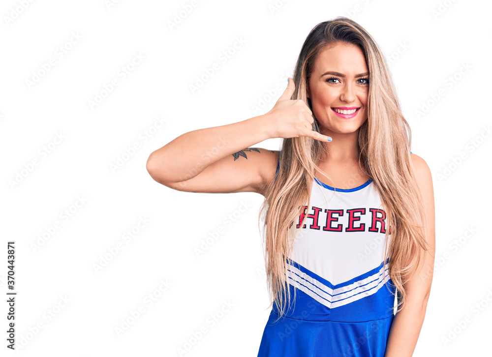 Young beautiful blonde woman wearing cheerleader uniform smiling doing phone gesture with hand and fingers like talking on the telephone. communicating concepts. Young beautiful blonde woman wearing cheerleader uniform smiling doing phone gesture with hand and fingers like talking on the telephone. communicating concepts.