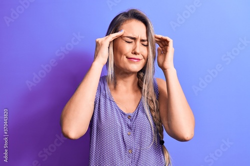 Young beautiful blonde woman wearing casual t-shirt standing over isolated purple background with hand on head, headache because stress. Suffering migraine.