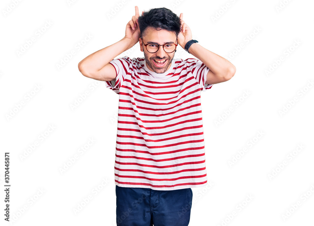 Young hispanic man wearing casual clothes posing funny and crazy with fingers on head as bunny ears, smiling cheerful Young hispanic man wearing casual clothes posing funny and crazy with fingers on head as bunny ears, smiling cheerful
