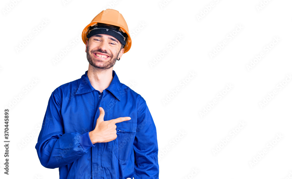 Young hispanic man wearing worker uniform cheerful with a smile on face pointing with hand and finger up to the side with happy and natural expression Young hispanic man wearing worker uniform cheerful with a smile on face pointing with hand and finger up to the side with happy and natural expression