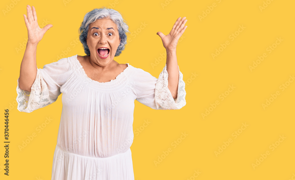 Senior woman with gray hair wearing bohemian style celebrating crazy and amazed for success with arms raised and open eyes screaming excited. winner concept Senior woman with gray hair wearing bohemian style celebrating crazy and amazed for success with arms raised and open eyes screaming excited. winner concept