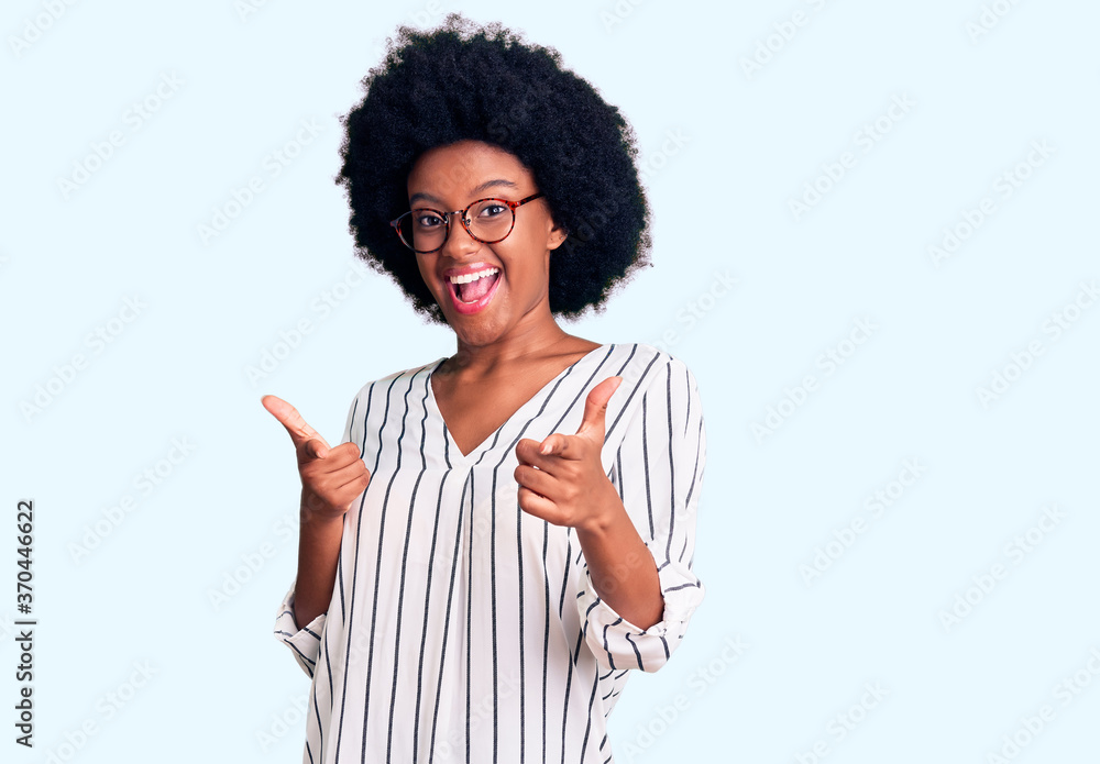 Young african american woman wearing casual clothes and glasses pointing fingers to camera with happy and funny face. good energy and vibes. Young african american woman wearing casual clothes and glasses pointing fingers to camera with happy and funny face. good energy and vibes.