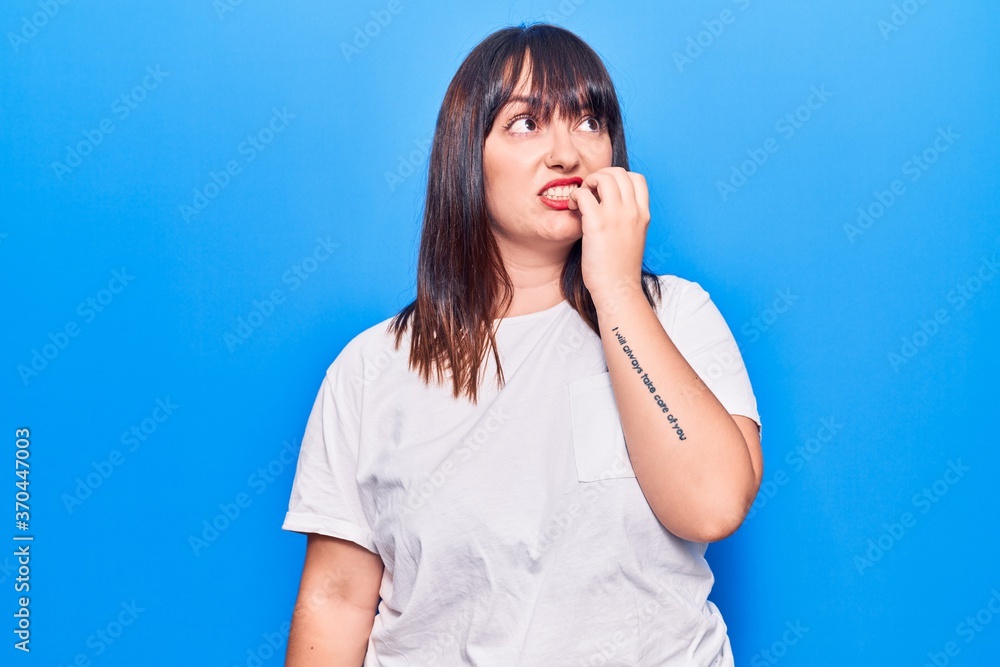 Young plus size woman wearing casual clothes looking stressed and nervous with hands on mouth biting nails. anxiety problem. Young plus size woman wearing casual clothes looking stressed and nervous with hands on mouth biting nails. anxiety problem.