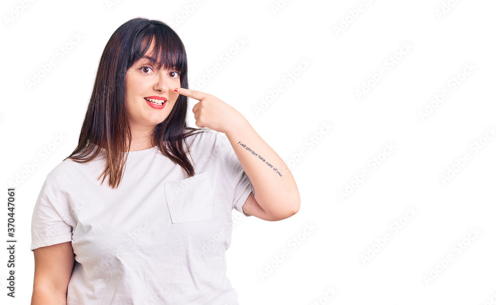 Young plus size woman wearing casual clothes pointing with hand finger to face and nose, smiling cheerful. beauty concept Young plus size woman wearing casual clothes pointing with hand finger to face and nose, smiling cheerful. beauty concept