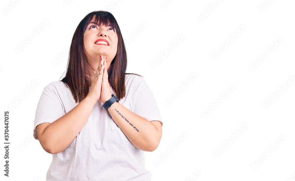 Young plus size woman wearing casual clothes begging and praying with hands together with hope expression on face very emotional and worried. begging. Young plus size woman wearing casual clothes begging and praying with hands together with hope expression on face very emotional and worried. begging.