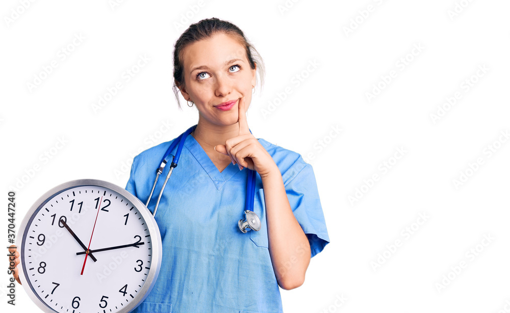 Young beautiful blonde woman wearing doctor uniform and stethoscope serious face thinking about question with hand on chin, thoughtful about confusing idea Young beautiful blonde woman wearing doctor uniform and stethoscope serious face thinking about question with hand on chin, thoughtful about confusing idea