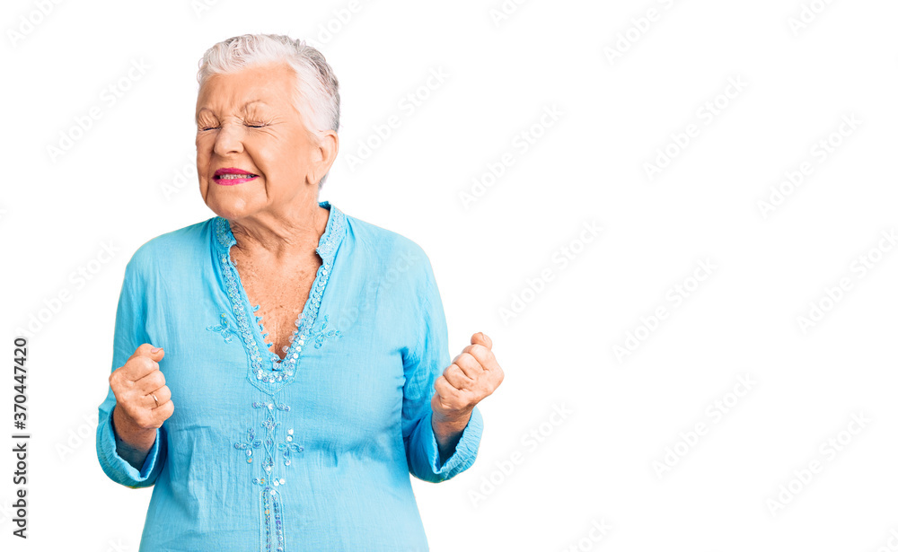 Senior beautiful woman with blue eyes and grey hair wearing summer dress excited for success with arms raised and eyes closed celebrating victory smiling. winner concept. Senior beautiful woman with blue eyes and grey hair wearing summer dress excited for success with arms raised and eyes closed celebrating victory smiling. winner concept.