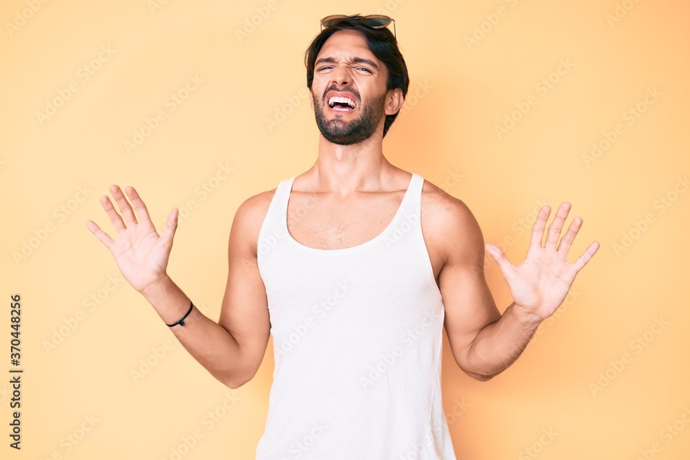 Handsome hispanic man wearing summer look and sunglasses afraid and terrified with fear expression stop gesture with hands, shouting in shock. panic concept. Handsome hispanic man wearing summer look and sunglasses afraid and terrified with fear expression stop gesture with hands, shouting in shock. panic concept.