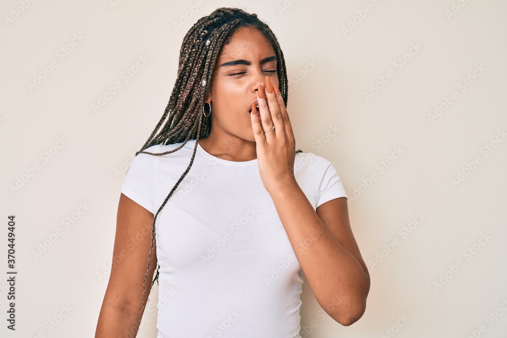 Young african american woman with braids wearing casual white tshirt bored yawning tired covering mouth with hand. restless and sleepiness. Young african american woman with braids wearing casual white tshirt bored yawning tired covering mouth with hand. restless and sleepiness.