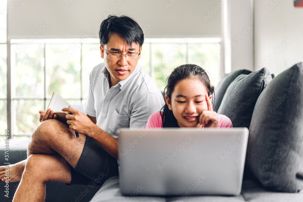 Father and asian kid little girl learning and looking at laptop computer making homework studying knowledge with online education e-learning system.children video conference with teacher tutor at home Father and asian kid little girl learning and looking at laptop computer making homework studying knowledge with online education e-learning system.children video conference with teacher tutor at home