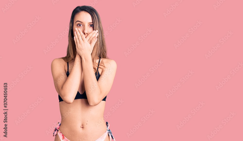 Fototapeta premium Young beautiful girl wearing bikini shocked covering mouth with hands for mistake. secret concept.