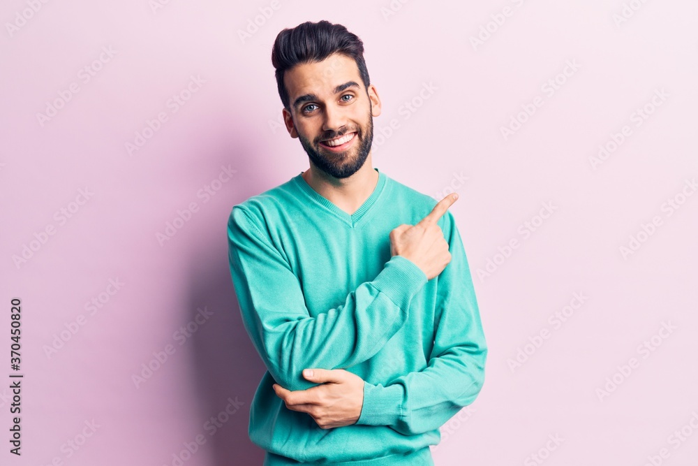 Young handsome man with beard wearing casual sweater smiling cheerful pointing with hand and finger up to the side Young handsome man with beard wearing casual sweater smiling cheerful pointing with hand and finger up to the side