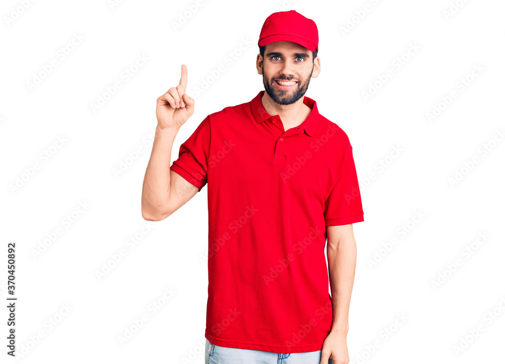 Young handsome man with beard wearing delivery uniform showing and pointing up with finger number one while smiling confident and happy. Young handsome man with beard wearing delivery uniform showing and pointing up with finger number one while smiling confident and happy.