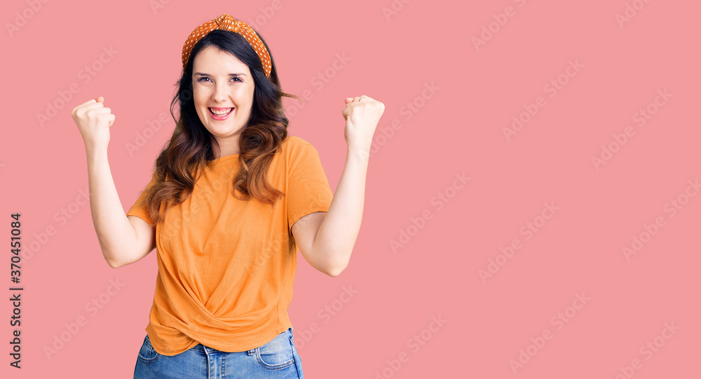 Beautiful young brunette woman wearing casual clothes screaming proud, celebrating victory and success very excited with raised arms Beautiful young brunette woman wearing casual clothes screaming proud, celebrating victory and success very excited with raised arms
