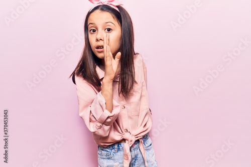Beautiful child girl wearing casual clothes hand on mouth telling secret rumor, whispering malicious talk conversation