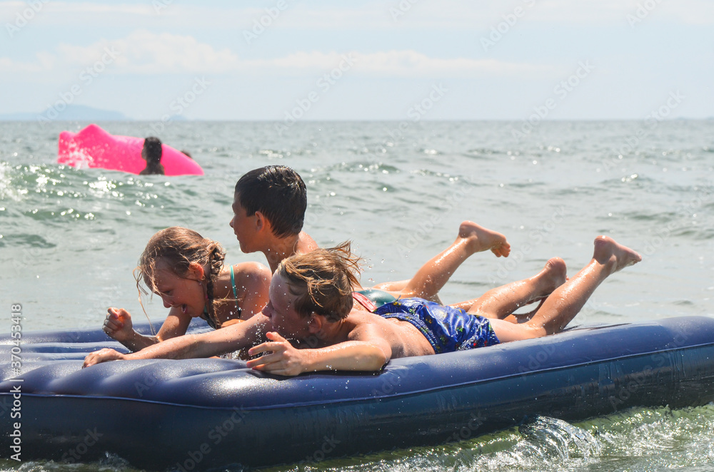 Obraz premium Caucasian children outdoor in summer swimming with inflatable mattress