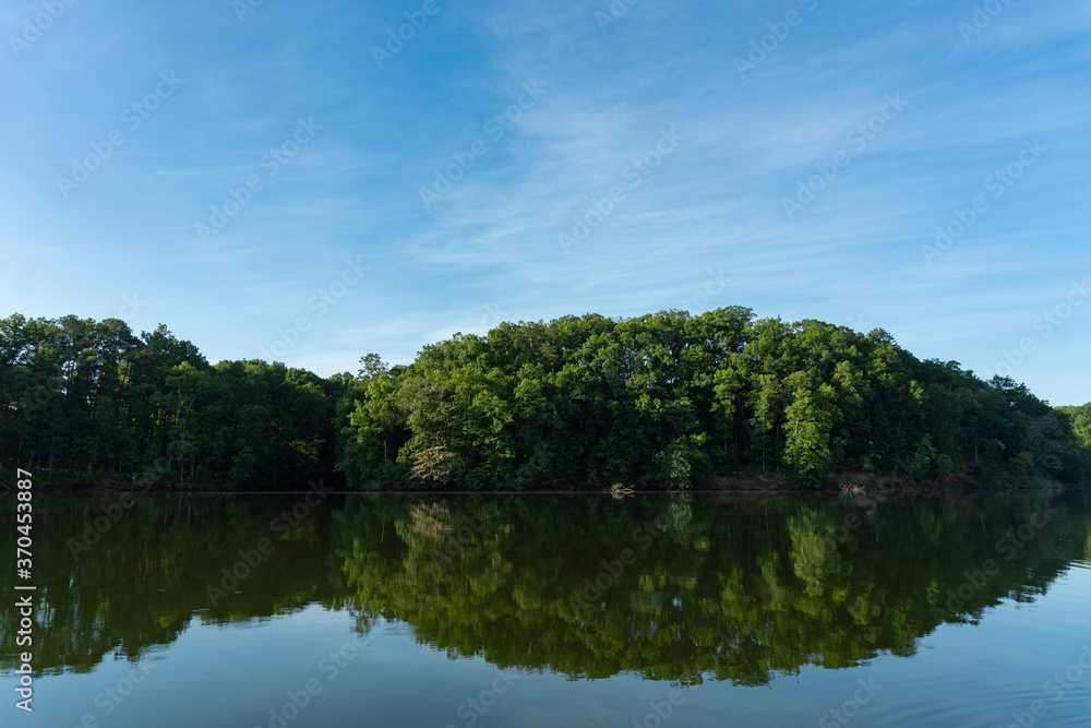 Reflection of green trees in the water on Lake Lanier under a blue sky in summer Reflection of green trees in the water on Lake Lanier under a blue sky in summer