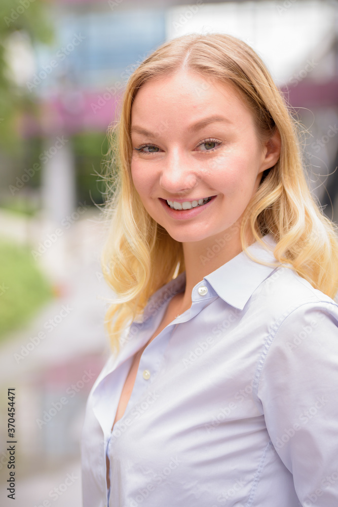 Face of happy young beautiful blonde businesswoman in the city with nature Face of happy young beautiful blonde businesswoman in the city with nature