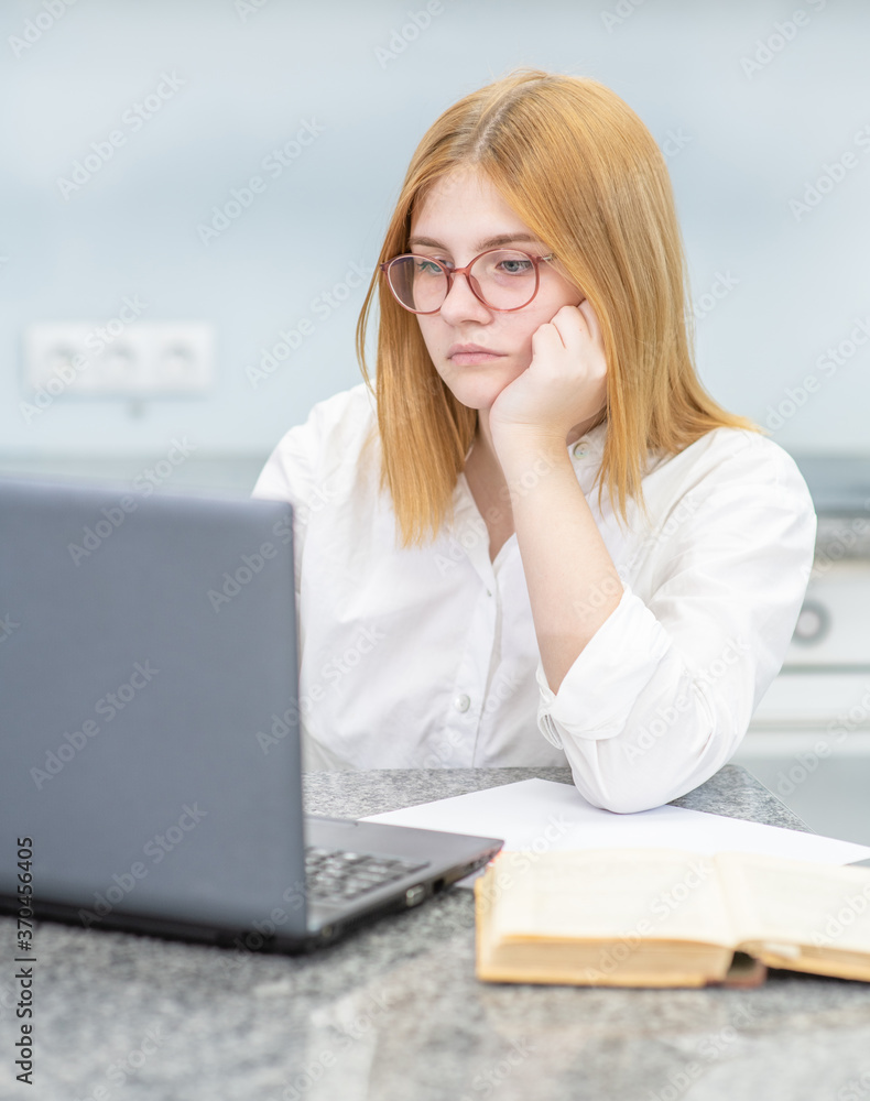 Pensive girl is doing homework with laptop at home. Distance learning Pensive girl is doing homework with laptop at home. Distance learning