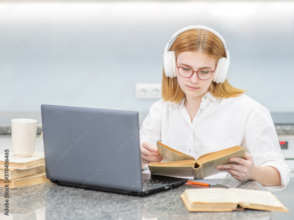 Young girl wearing headphones studying online with a laptop. Distance learning concept concept