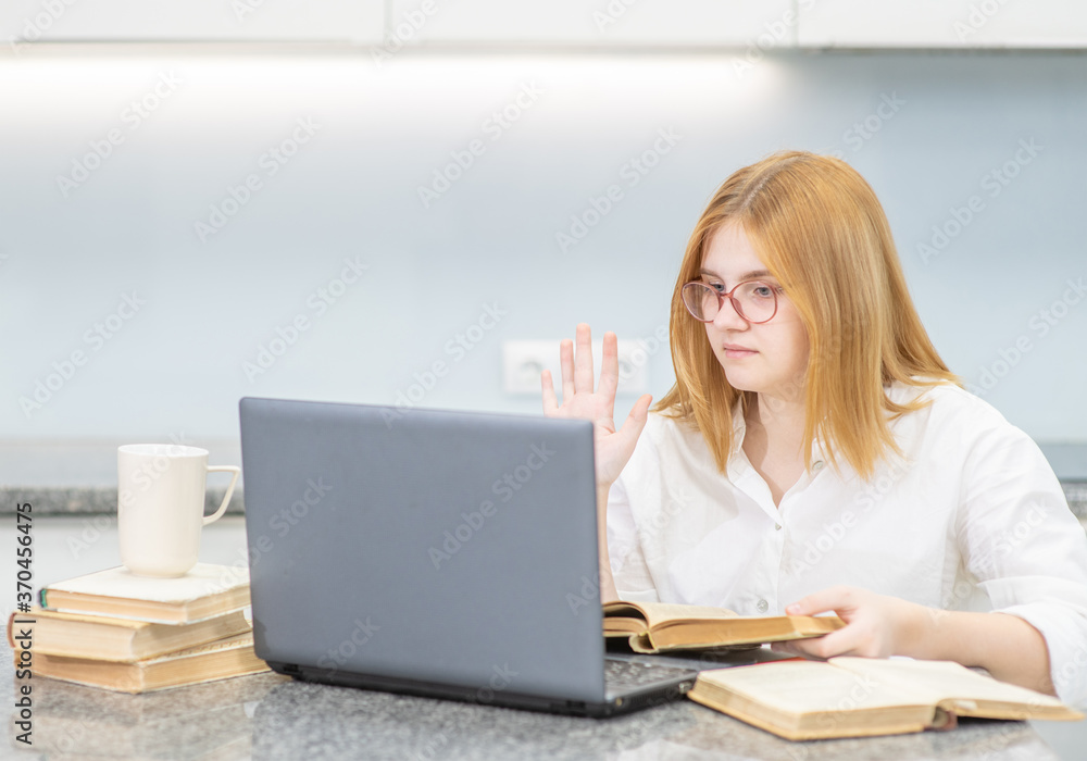 Smart teen girl read a book and uses laptop at home. Distance learning concept Smart teen girl read a book and uses laptop at home. Distance learning concept