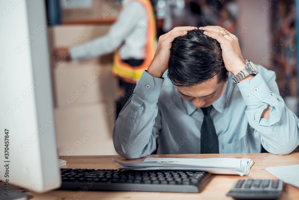 Stressed businessman worry about financial balance trouble of his company at his office in warehouse. Profit less than target while global corona virus or Covid-19 crisis, negative emotional concept Stressed businessman worry about financial balance trouble of his company at his office in warehouse. Profit less than target while global corona virus or Covid-19 crisis, negative emotional concept