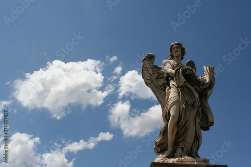 statue of angel with garment and dice in blue sky background