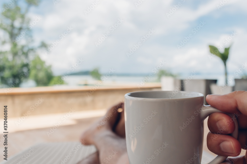 Man drinks coffee on the balcony by the sea in concept of relaxation and vacation. Man drinks coffee on the balcony by the sea in concept of relaxation and vacation.