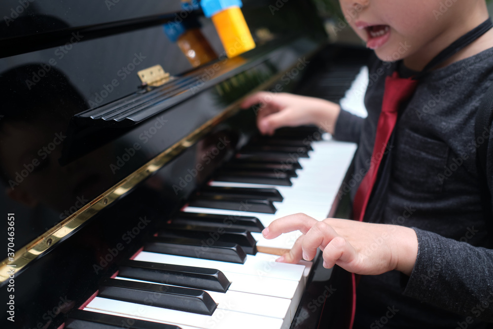 Obraz premium Little Asian kid boy playing piano in living room at home, Preschool child having fun with learning to play music instrument, Music education concept, Soft and selective focus