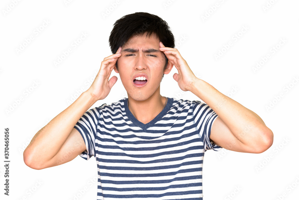 Studio shot of young Asian man having headache and looking at camera isolated against white background Studio shot of young Asian man having headache and looking at camera isolated against white background