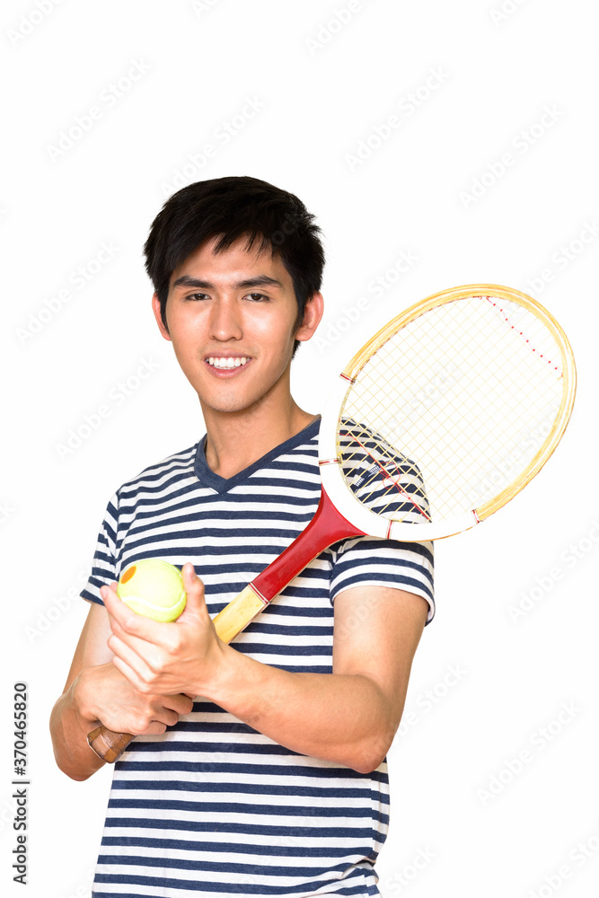 Studio shot of young handsome Asian man holding tennis racket isolated against white background Studio shot of young handsome Asian man holding tennis racket isolated against white background