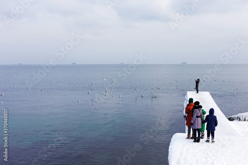 Odessa, Ukraine - January 10, 2017: People walk on the city's seaside promenade. Snow and ice. Icing after a strong winter storm with strong frosts.
