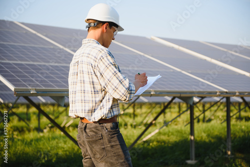 Solar power plant. Man standing near solar panels. Renewable energy. © Serhii