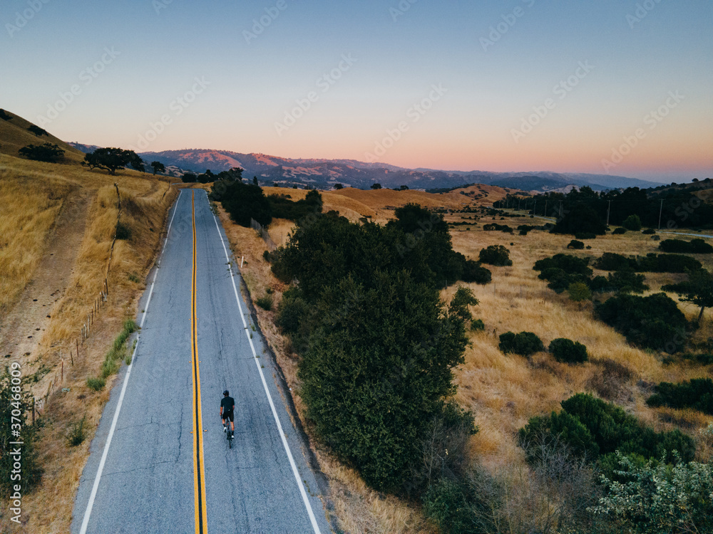 Obraz premium Solo bike rider on straight country road, drone aerial