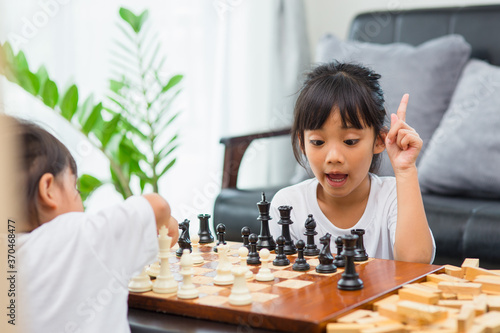 Two cute children playing chess at home